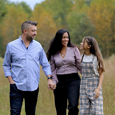 Kevin holding hands with wife and daughter in a field