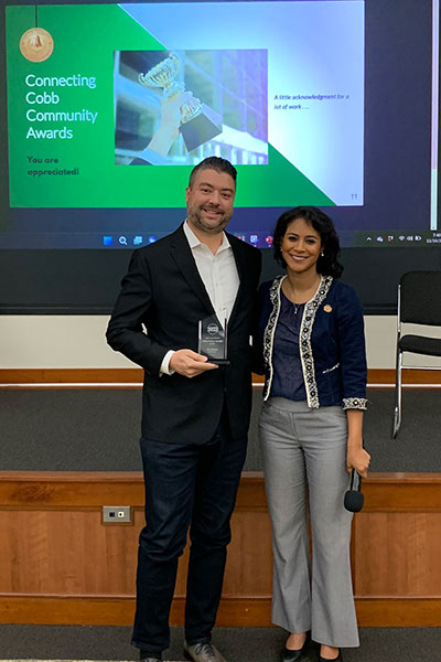 Kevin standing next to commissioner Jerica Richardson accepting an award