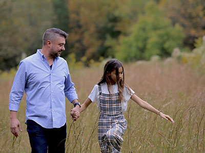 Kevin holding hands with his daughter looking down into a field