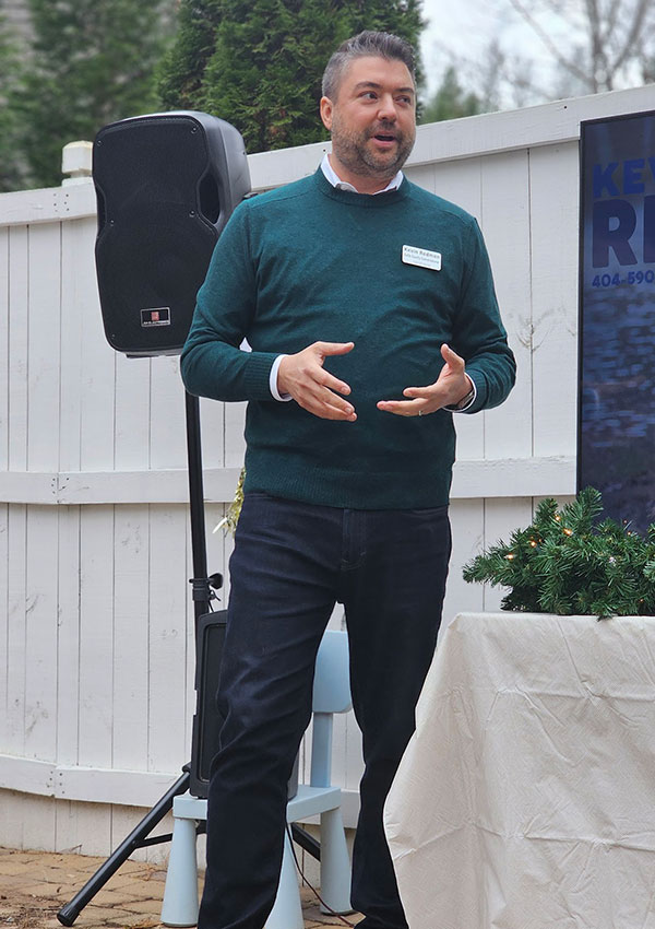 Kevin standing in casual clothes on patio speaking to a group of people